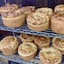 Two shelves from the metal rack that are covered by round, finished paska breads, which have a dough braid running around their circumferences and an Orthodox cross in the center.