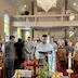A view very similar to the one in the previous photo except that this picture was taken from directly in front of Fr. Aleksey, so everyone is visible in a more straight-on manner, and now the choir loft is also visible, with a man on either side looking down toward the center table, where Fr. Aleksey is reading.